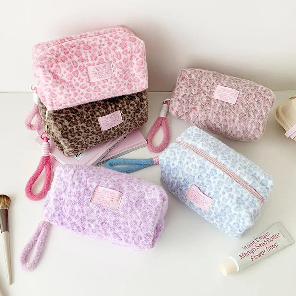 A collection of pink and purple leopard print plush cosmetic pouches and a bamboo beauty tool.