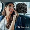 A woman wearing glasses is using a phone while sitting in a car, with leopard print headrest covers visible on the seat.
