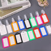 A collection of colorful, customizable luggage tags in various shades of pink, orange, blue, and green are displayed on a gra
