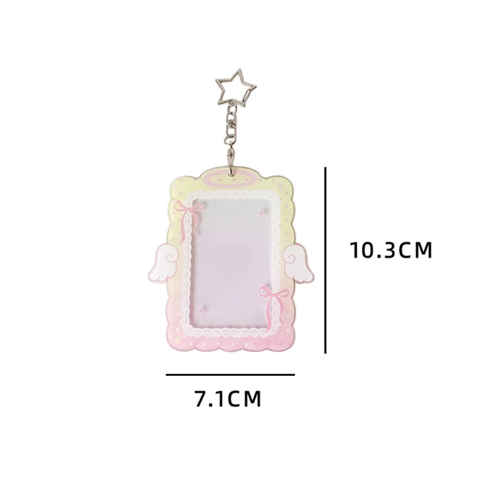 A clear display case framed with pink lace and featuring angel wings, suspended by a star charm.