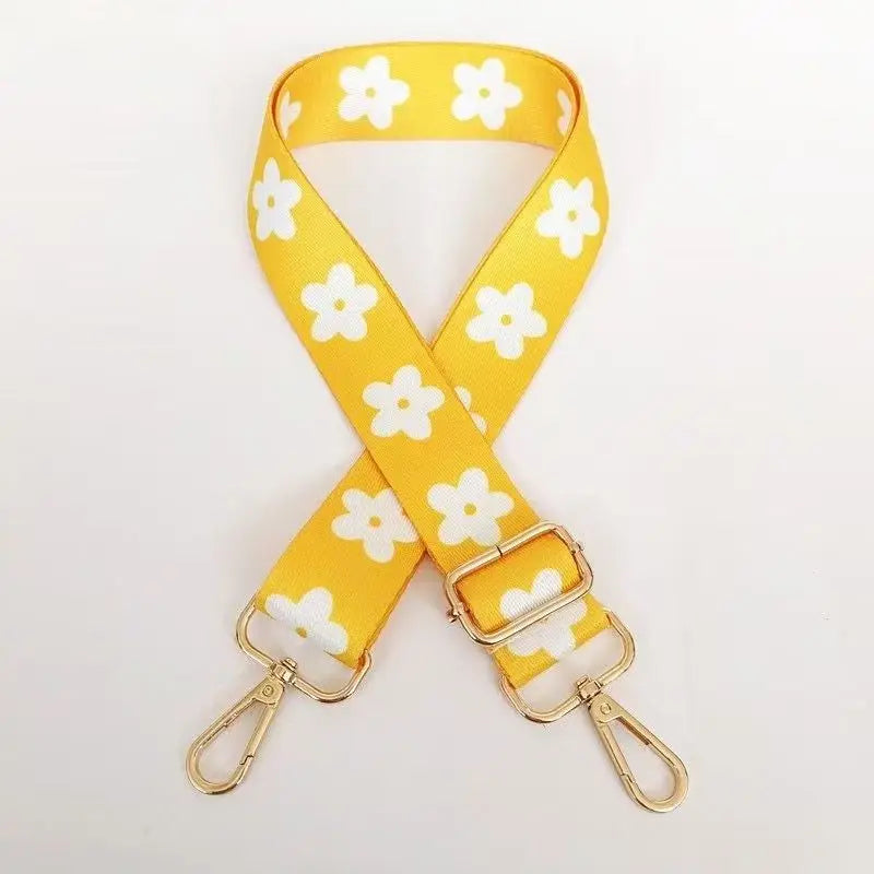 Yellow nylon bag strap with a floral pattern, featuring gold-toned hardware.
