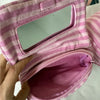 A pink striped makeup bag with a flip-top mirror is shown being held open.