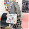 A woman models a white Y2K punk goth crossbody bag with pink accents and plaid pants.