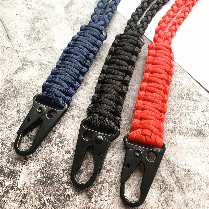 Three hand-woven nylon lanyards in blue, black, and red with metal hooks displayed on a gray surface.