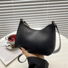 A black retro solid color PU leather shoulder bag with a gold-toned zipper and strap resting on a white surface.