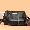 A black luxury cowhide shoulder bag with tan accents and stitching, shown in a studio setting.