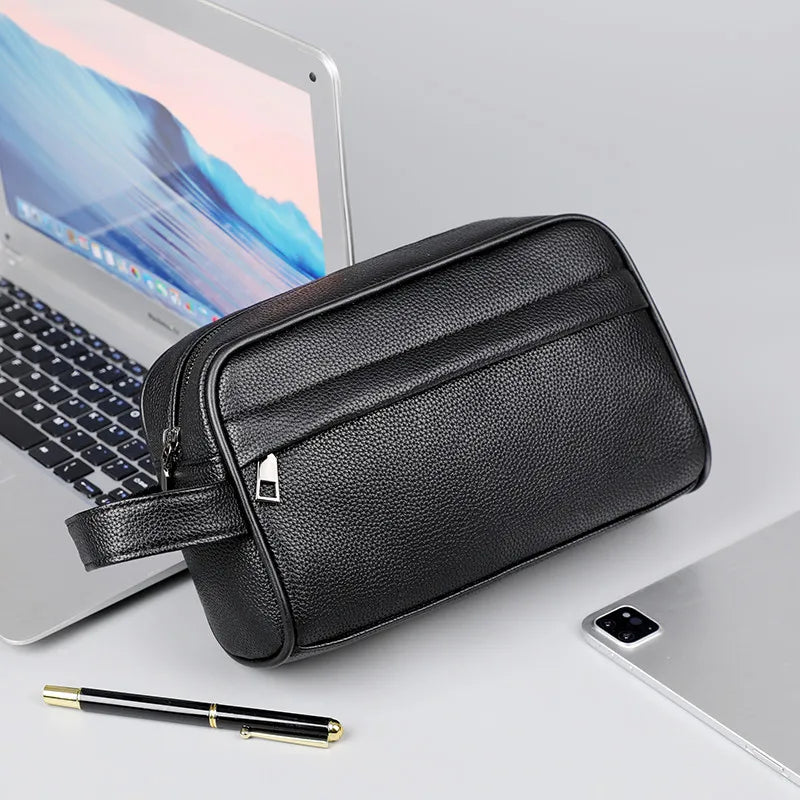 A black PU leather crossbody bag is shown next to a silver laptop and a pen on a white surface.