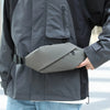 Graue minimalistische Lauf-Tauschtasche, befestigt an einer dunkelgrauen Jacke.