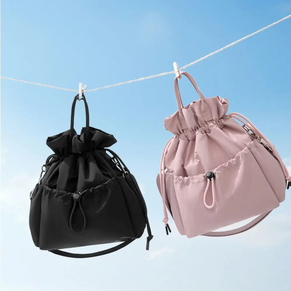 A pink insulated waterproof lunch bag hanging on a clothesline against a blue sky.