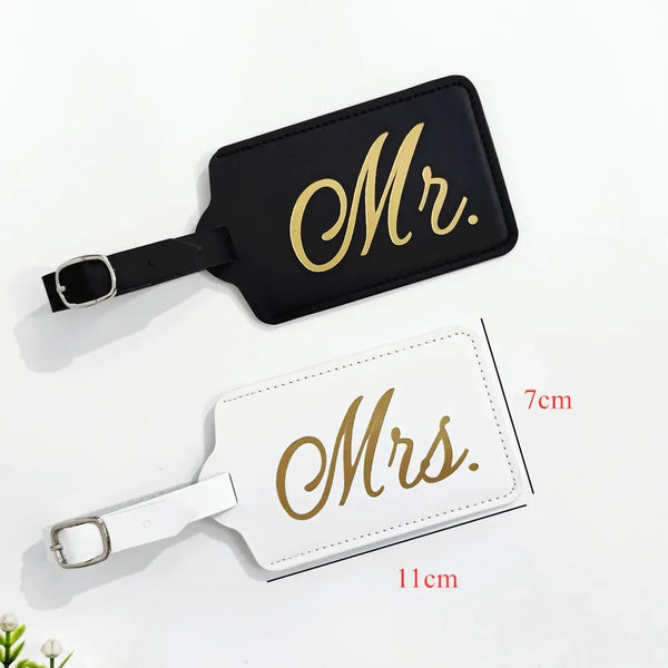 A pair of personalized luggage tags, one gold embossed Mr. and one gold embossed Mrs., on a white background.