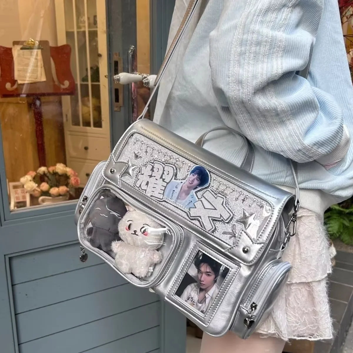 A silver transparent PU crossbody bag featuring a cat charm and a photo print on the front, carried by a person.