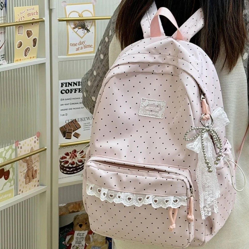 A pink polka dot nylon travel backpack with a laptop compartment and lace trim.