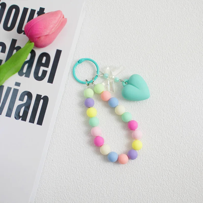 A colorful bead necklace featuring pink, yellow, and blue beads with a heart charm attached to an O-ring clip.
