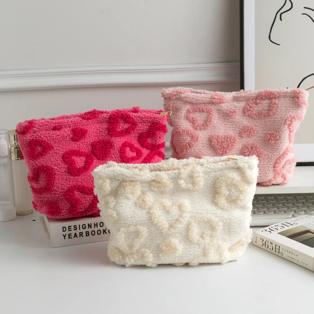 Two plush heart-pattern storage bags in pink and cream colors resting on a white surface.