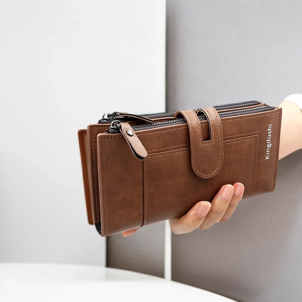 A hand holds a brown leather wallet with a zipper closure and the brand name Kingdushi.