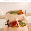 A light pink insulated lunch bag is shown open, filled with fresh fruits and vegetables on a wooden table.