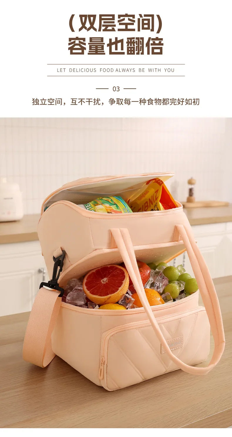 A light pink insulated lunch bag is shown open, filled with fresh fruits and vegetables on a wooden table.