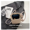 Bolso cruz de cuero beige con un smartphone oscuro sobre un fondo de tela gris.