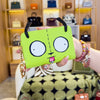 A hand holds a lime green cartoon character coin purse wallet with large eyes and a pink beaded bracelet.