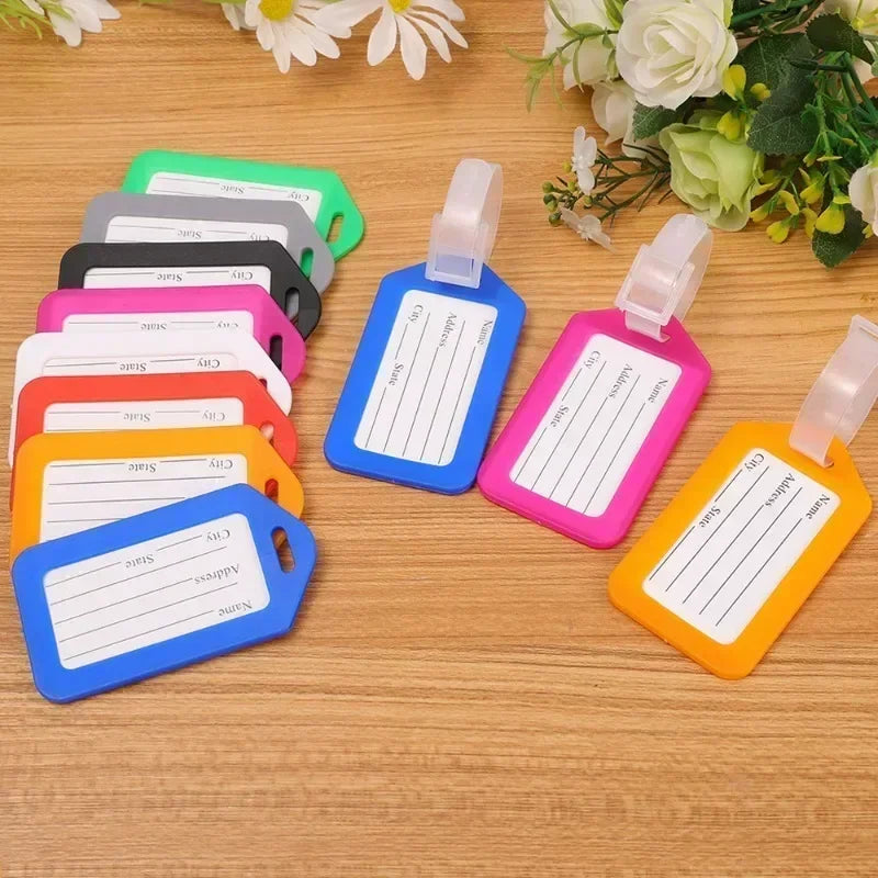 A collection of colorful, customizable luggage tags in various shades of green, pink, yellow, and blue, arranged on a wooden 