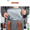 Una bolsa térmica gris con la tapa abierta sostenida por una persona, mostrando sus características de aislamiento.