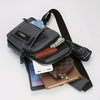 A black adjustable crossbody sling bag with multiple compartments and a strap is shown next to a smartphone and wallet.