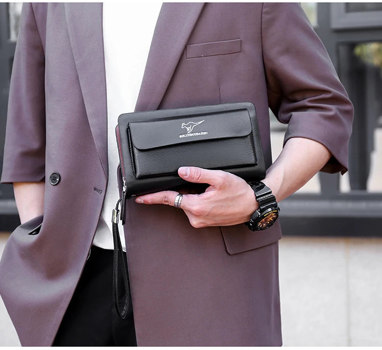 Une personne tient un porte-monnaie à pochette en PU brun foncé avec une fermeture éclair double sur le revers d'un manteau t