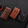 Three leather belt loop phone cases in brown and black colors displayed on a dark surface.