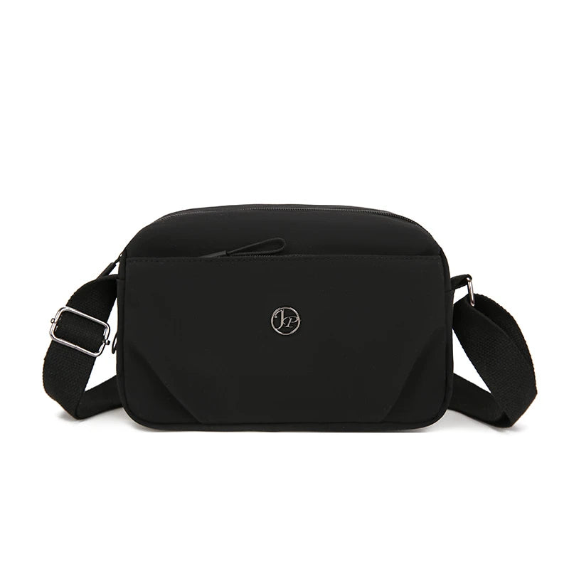 Bolso cruz de nylon impermeable negro con logo plateado y correa ajustable.