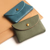 A stack of two genuine leather card holders or coin purses in shades of blue-green and olive green.