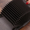 Une pile de pochettes et porte-cartes de luxe noires sur une surface en bois foncé.