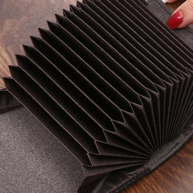Une pile de pochettes et porte-cartes de luxe noires sur une surface en bois foncé.