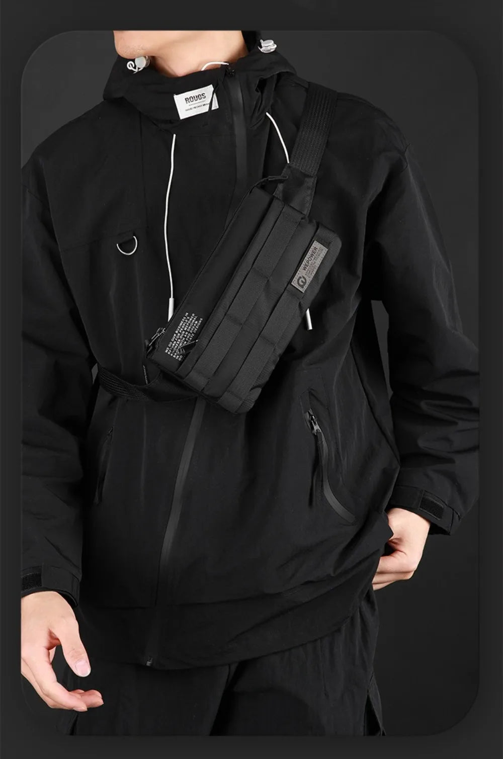 A person wearing a black hoodie with a black chest bag slung across the body.