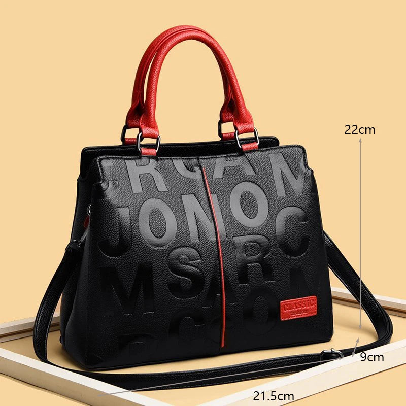 Sac bandoulière en cuir PU noir avec poignée rouge et texte gravé sur le devant.