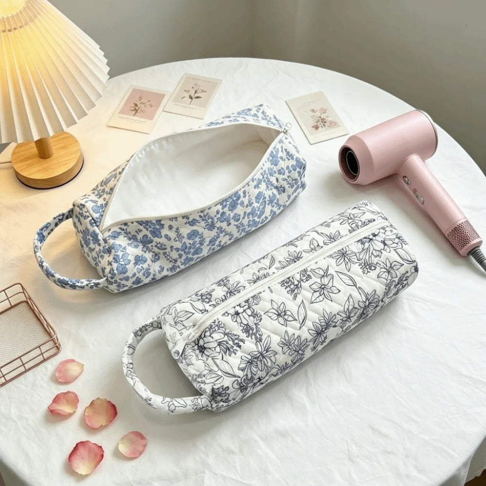 A light blue and white floral quilting storage bag is displayed on a white table next to a pink hair dryer.