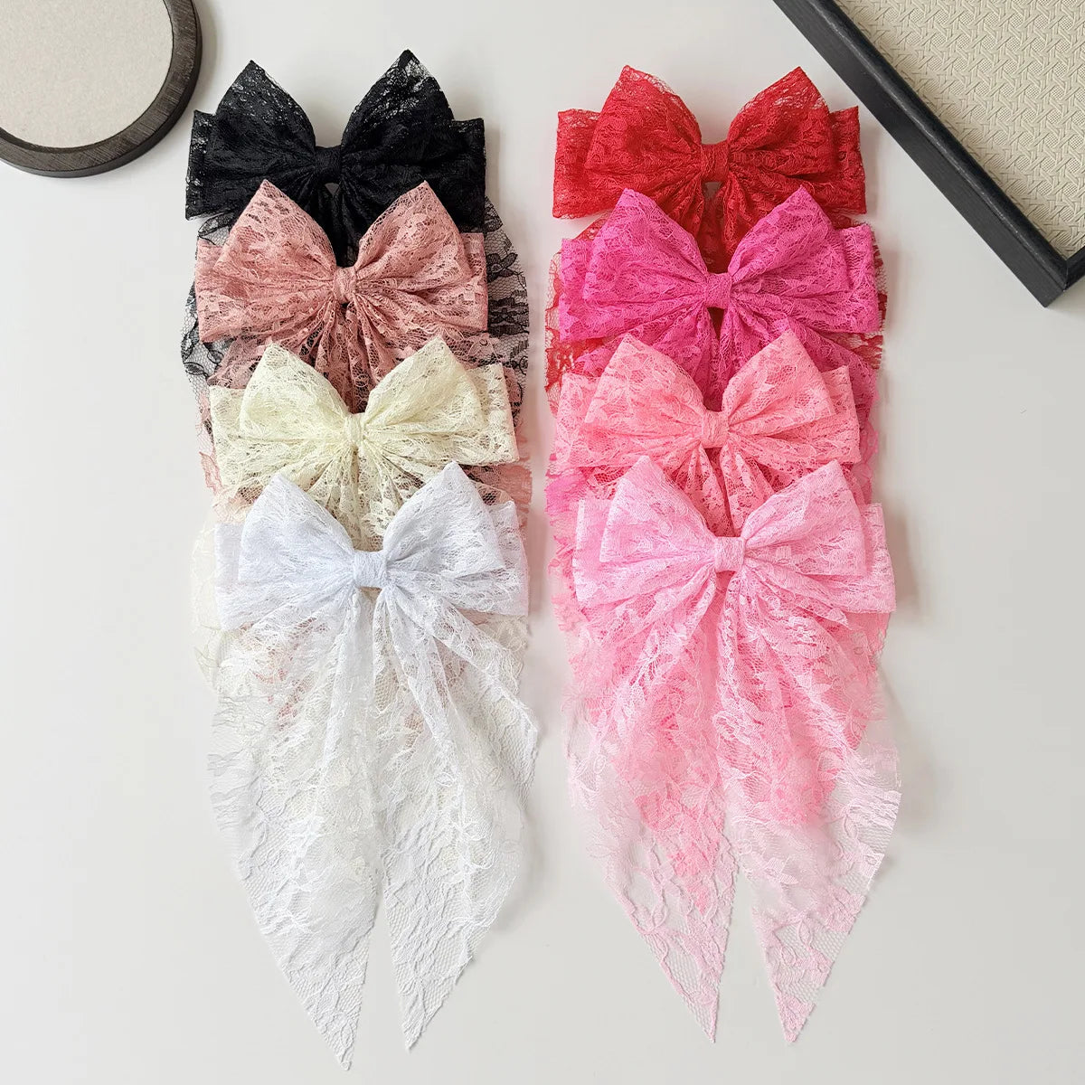 Eine Sammlung von rosa, roten, schwarzen und weißen Spitzen-Haarspangen auf einer hellen Oberfläche.