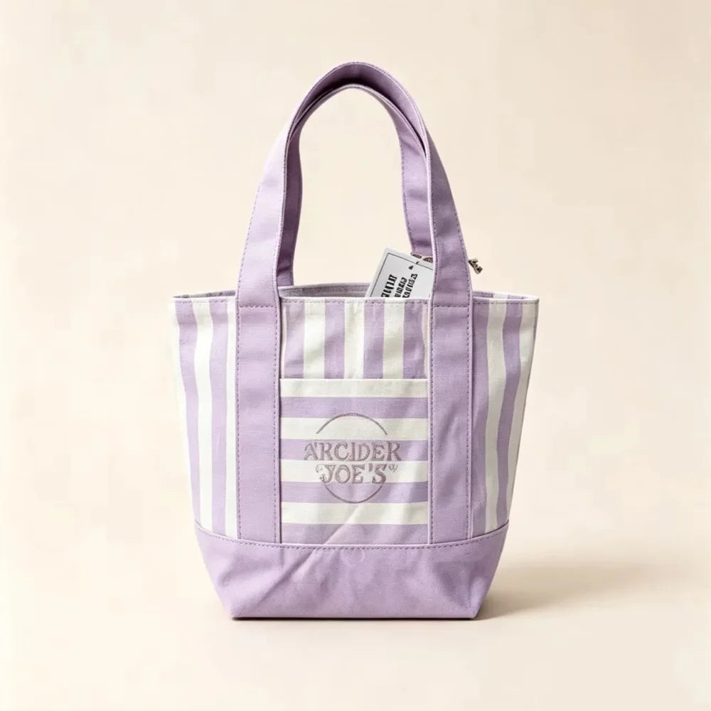 Bolso de lona a rayas morado y blanco con asa y etiqueta pequeña.