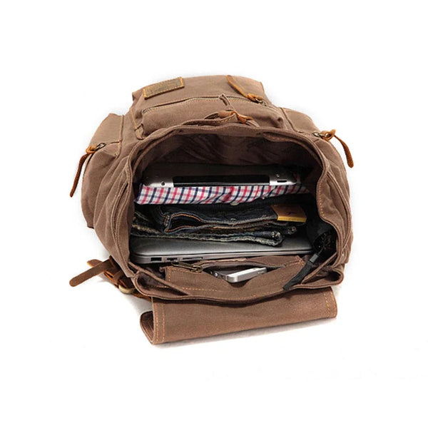 A brown vintage canvas men's backpack is open, showing various small items inside.