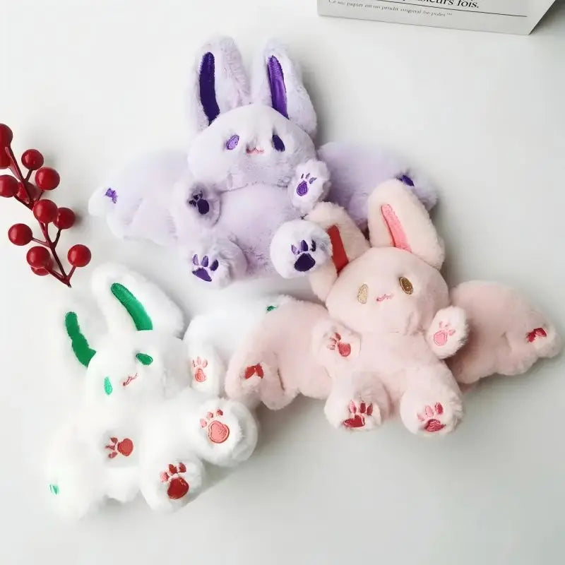 A collection of soft stuffed bunny plush toys in purple, pink, and white colors.