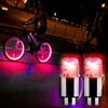 A pair of bright pink LED tire valve stem lights are shown illuminating a dark road at night.