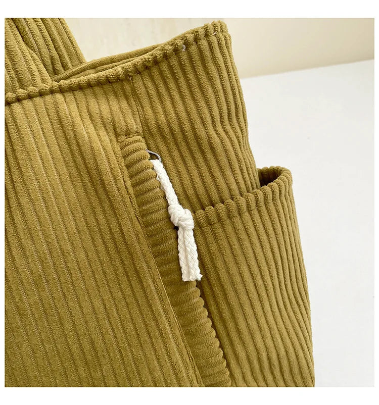 Close-up of a mustard green corduroy casual handbag with a white drawstring detail.