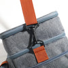 A close-up of a gray insulated lunch bag with orange straps and blue zippers.