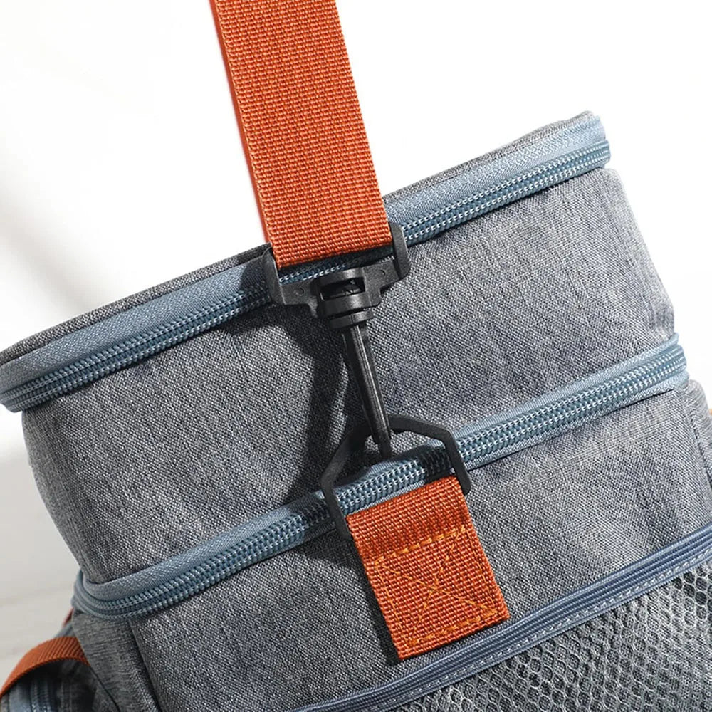 A close-up of a gray insulated lunch bag with orange straps and blue zippers.