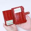 A hand holds a red crocodile pattern leather card holder with a zipper, displaying several cards.