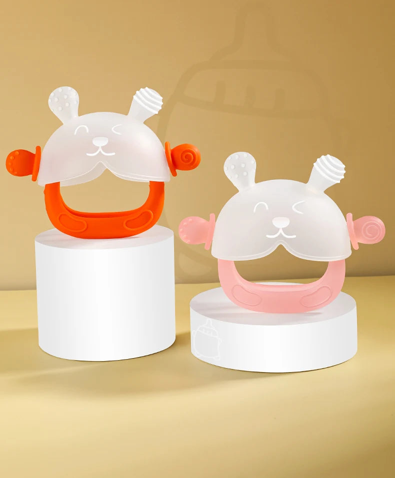 A set of silicone teethers shaped like cute bunnies in white and orange colors displayed on a light wooden surface.