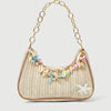 A beige woven straw shoulder bag adorned with colorful ocean charms and a gold chain strap.