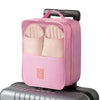 A pink portable luggage shoe organizer bag with multiple compartments resting on a gray suitcase.