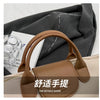 A brown vintage PU leather crossbody handbag is shown against a dark gray fabric background.