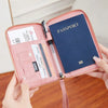 A hand opens a pink RFID-blocking passport wallet showing various documents and a passport inside.