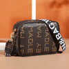 A brown leather fashion crossbody shoulder bag with gold hardware and a black and white striped strap.